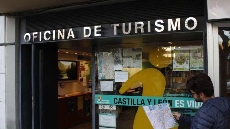 Un joven mira un mapa enfrente de la Oficina de Turismo.