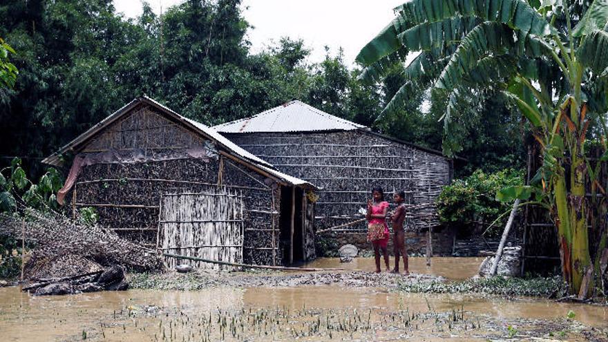 Dos jóvenes junto a unas casas afectadas por inundaciones en el distrito de Saptari.