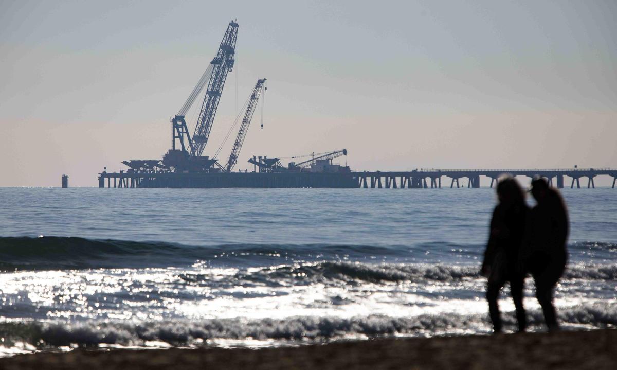 Vecinos del Port de Sagunt observan desde la playa la retirada de las tolvas del Pantalán