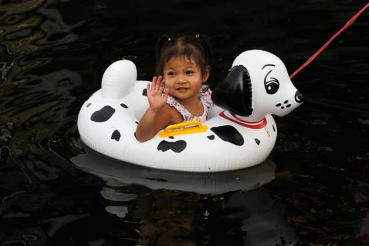 Una nena saluda des del seu flotador mentre navega per un carrer inundat de Bangkok.