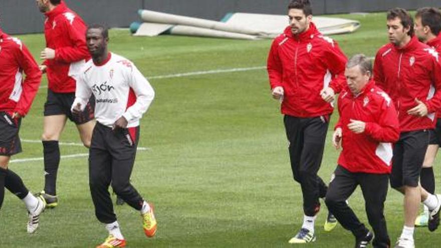 Mendy, a la izquierda, con sudadera blanca, realiza ejercicios de calentamiento junto a sus compañeros y Javier Clemente, durante el entrenamiento de ayer en El Molinón.