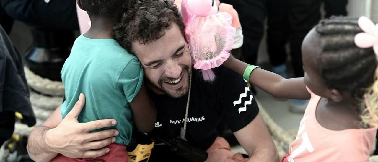 Un miembro de la tripulación del &quot;Aquarius&quot; se abraza a unos niños que viajaban a bordo del buque, a su llegada, ayer, al puerto de Valencia.