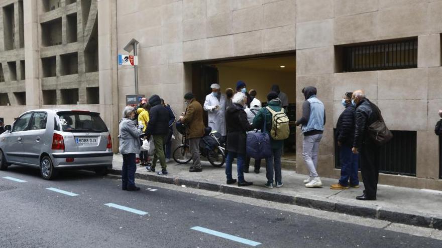 Un grupo de personas hacen fila a las puertas del comedor social del Carmen en Zaragoza. | ANDREEA VORNICU