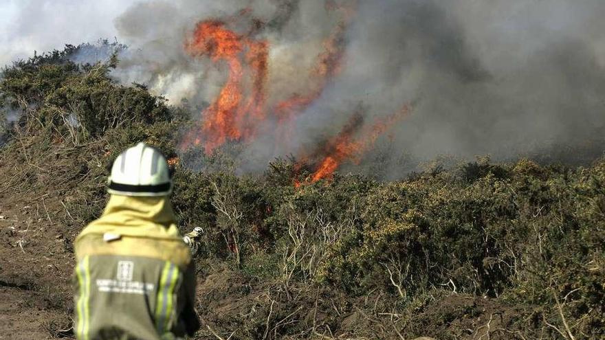 Un operario trata de apagar las llamas en el incendio de Covas, en Ferrol, ayer. // Efe/Kiko Delgado