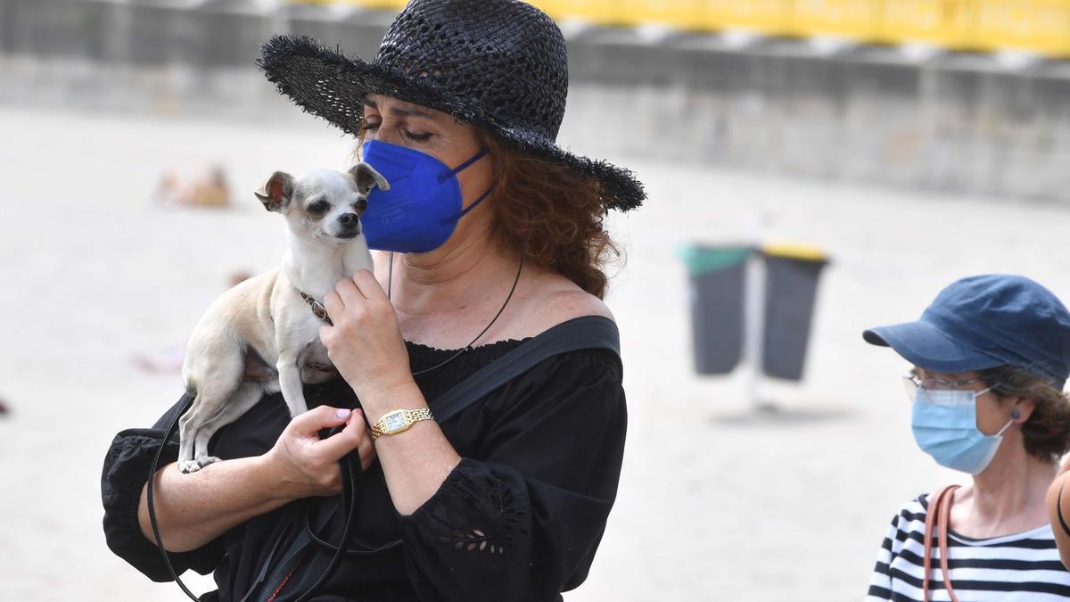 Varias personas en el paseo marítimo de A Coruña junto a la playa de Riazor.