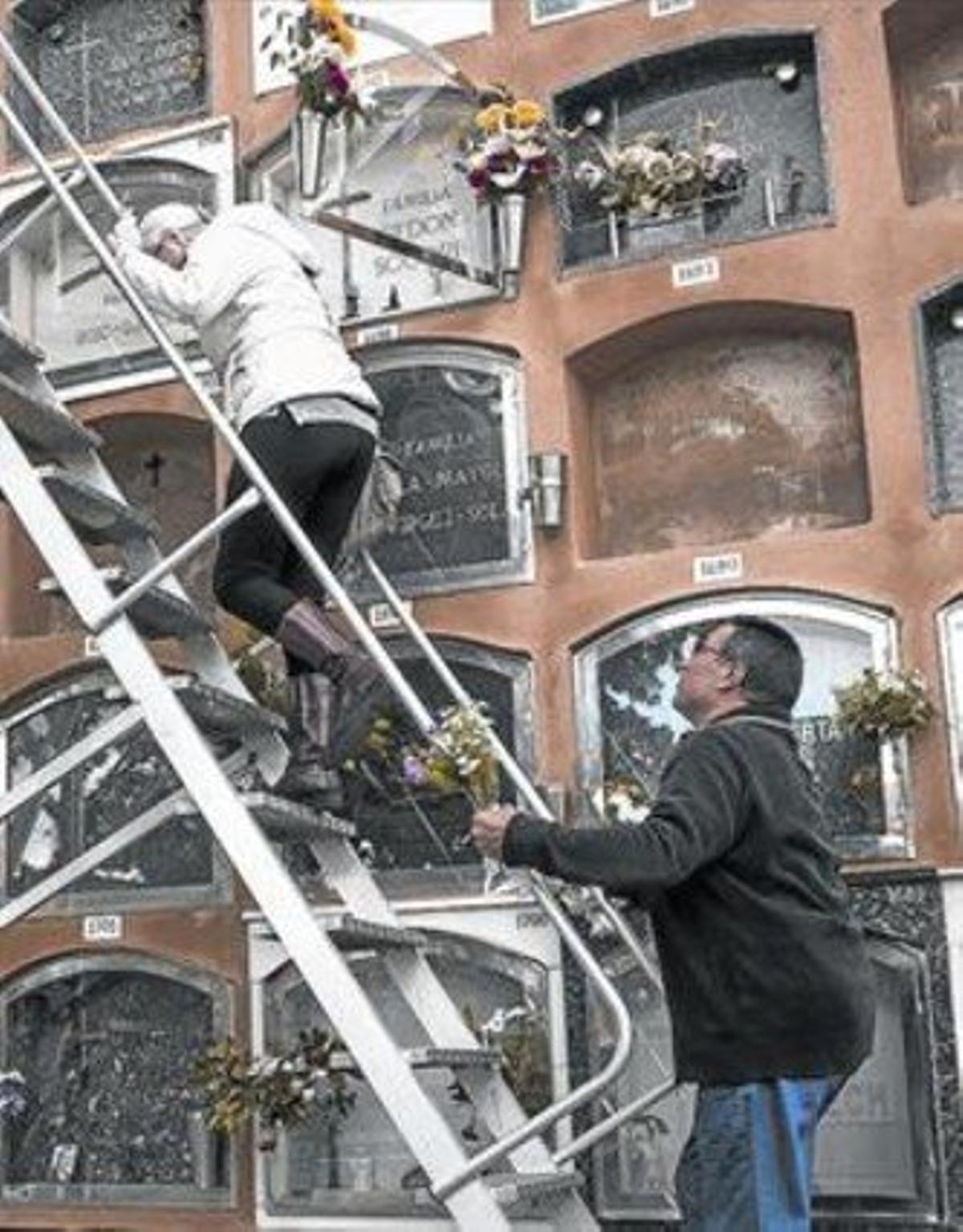 Un hombre ayuda a una señora con la escalera para acceder a los nichos superiores