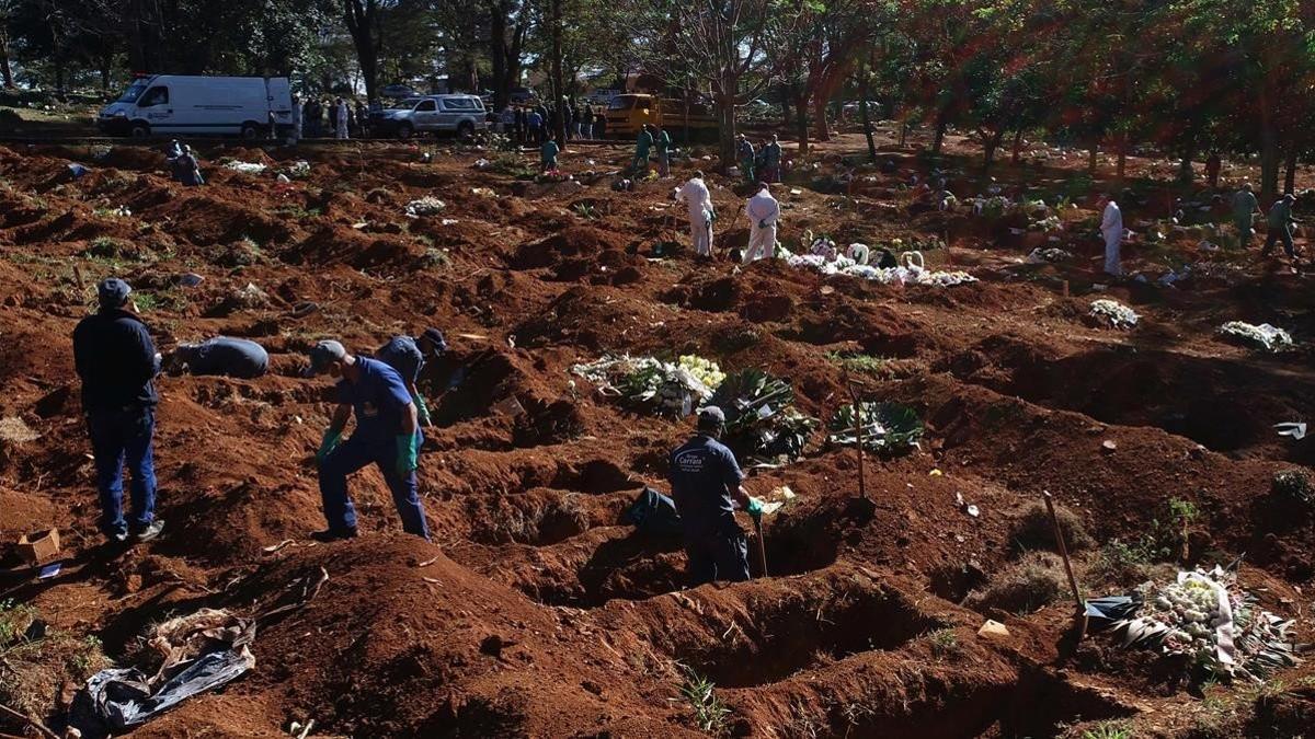 Trabajadores entierran a víctimas de covid-10 en un cementerio de Sao Paulo.