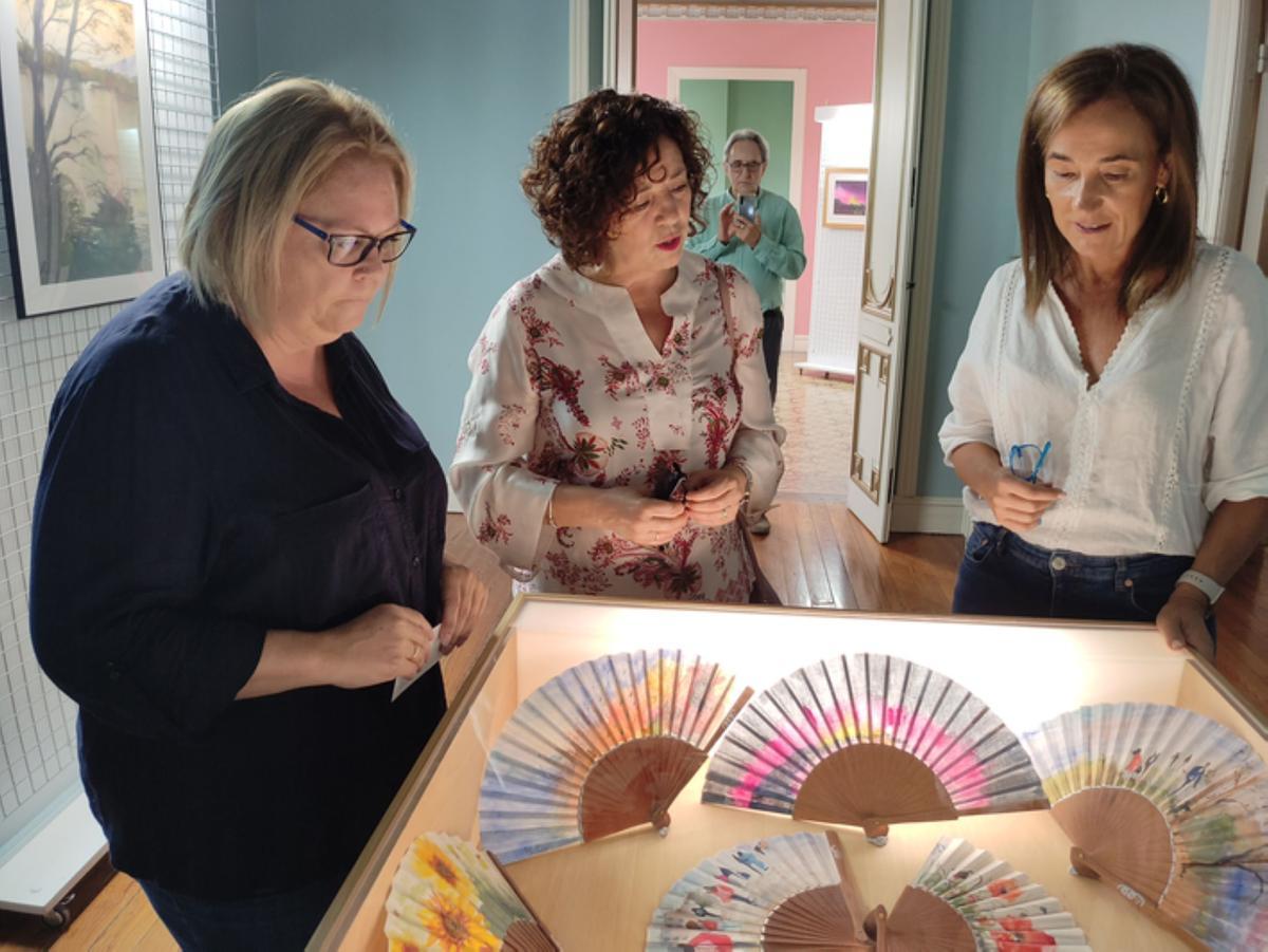 Muestra de abanicos pintados a base de acuarela y la artista, en el medio. / E. P.