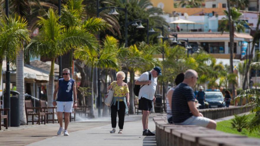 Un grupo de personas pasean por una zona peatonal de la playa de Las Vistas, en el municipio sureño de Arona.