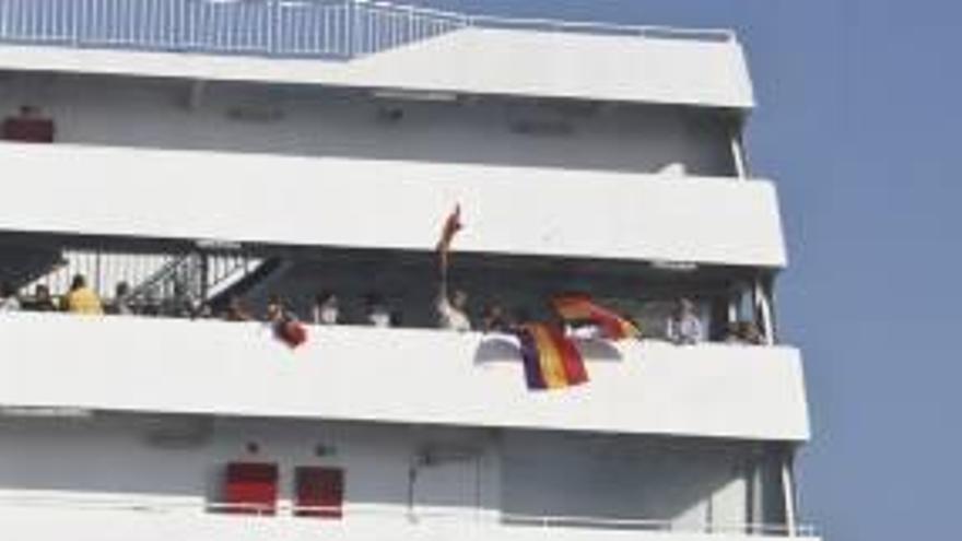 Algunos de los viajeros se despiden del ferry portando banderas republicanas.