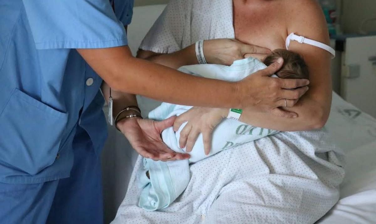 Una madre amamanta a su bebé con la ayuda de una matrona.