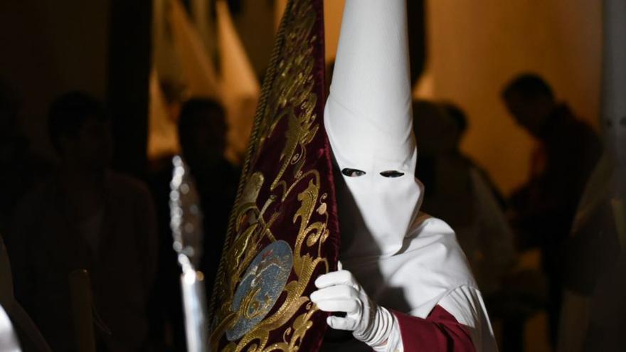 Nazareno de la hermandad de la Sentencia portando el estandarte.