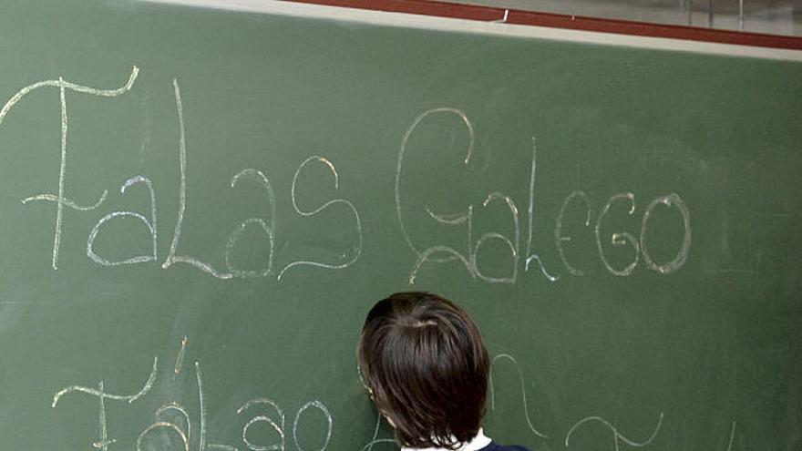 Un escolar escribe en gallego en el encerado.