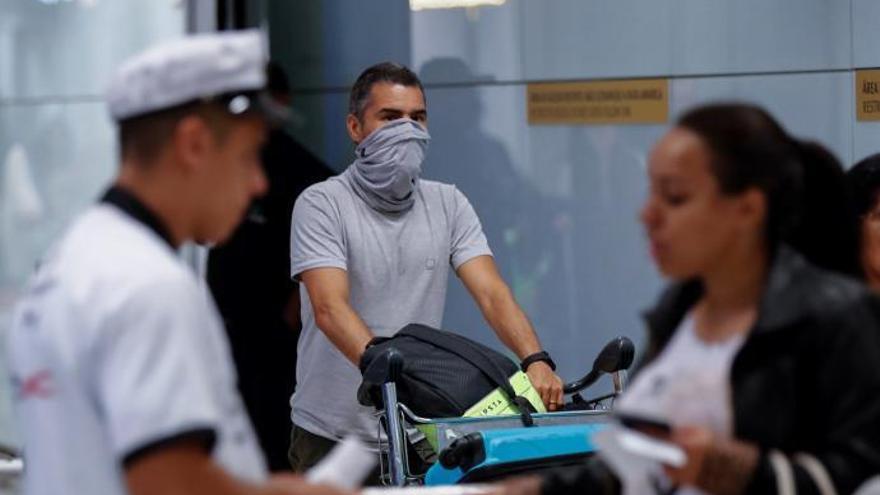 Un hombre se cubre el rosto en el aeropuerto.