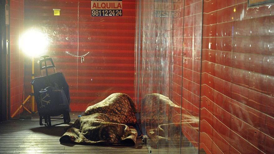 Una persona sin hogar duerme en el portal de un comercio vacío.   | // VÍCTOR ECHAVE
