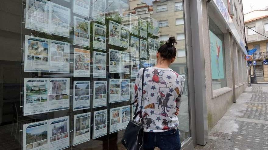 Una joven observa las ofertas de alquiler en una inmobiliaria.