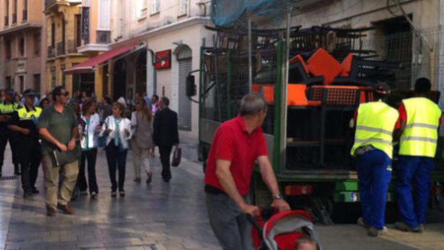 Imagen de los operarios, retirando el mobiliario de una de las terrazas apercibidas en Calle Granada.