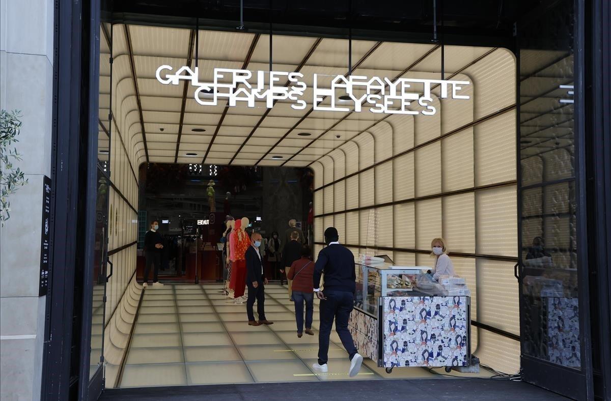 Clientes que esperan entrar en la emblemática tienda Galeries Lafayette de Avenue des Champs-Elysees 