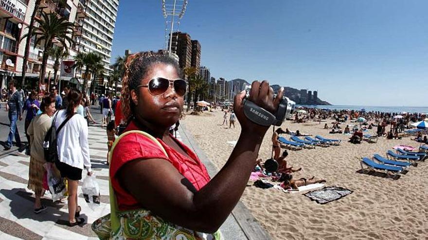 Una turista graba con su cámara la playa de Levante de Benidorm.