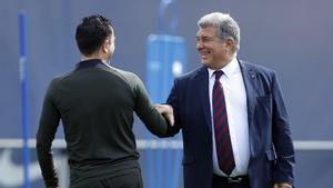 Xavi saluda a Joan Laporta durante el último entrenamiento previo al duelo europeo con el PSG en Montjuïc.