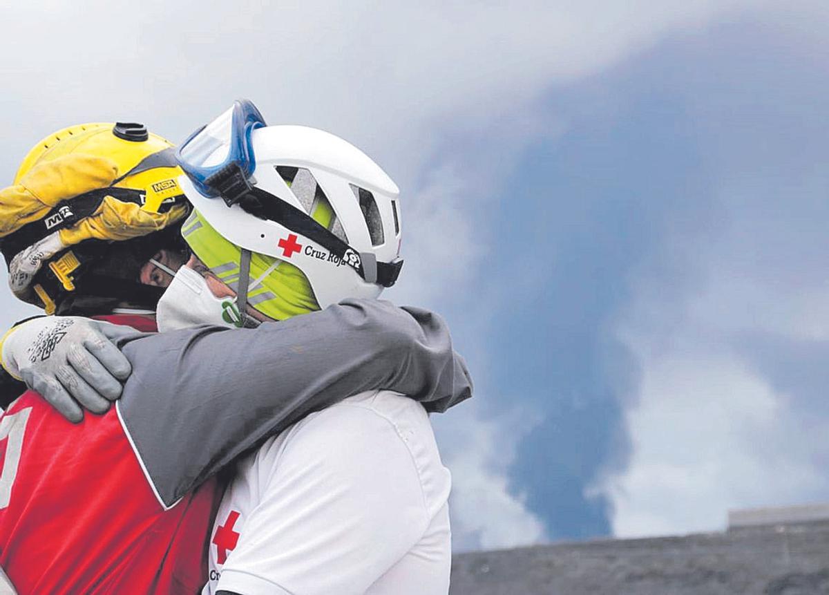 Dos voluntarios se abrazan durante la erupción en La Palma del volcán Tajogaite, en La Palma.