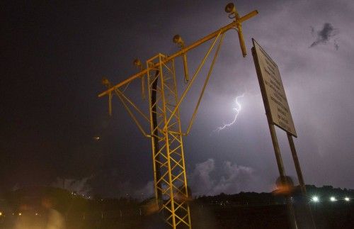 A lightning flashes in the sky above the Alder airport as people pass by a light post in the Adler district of Sochi