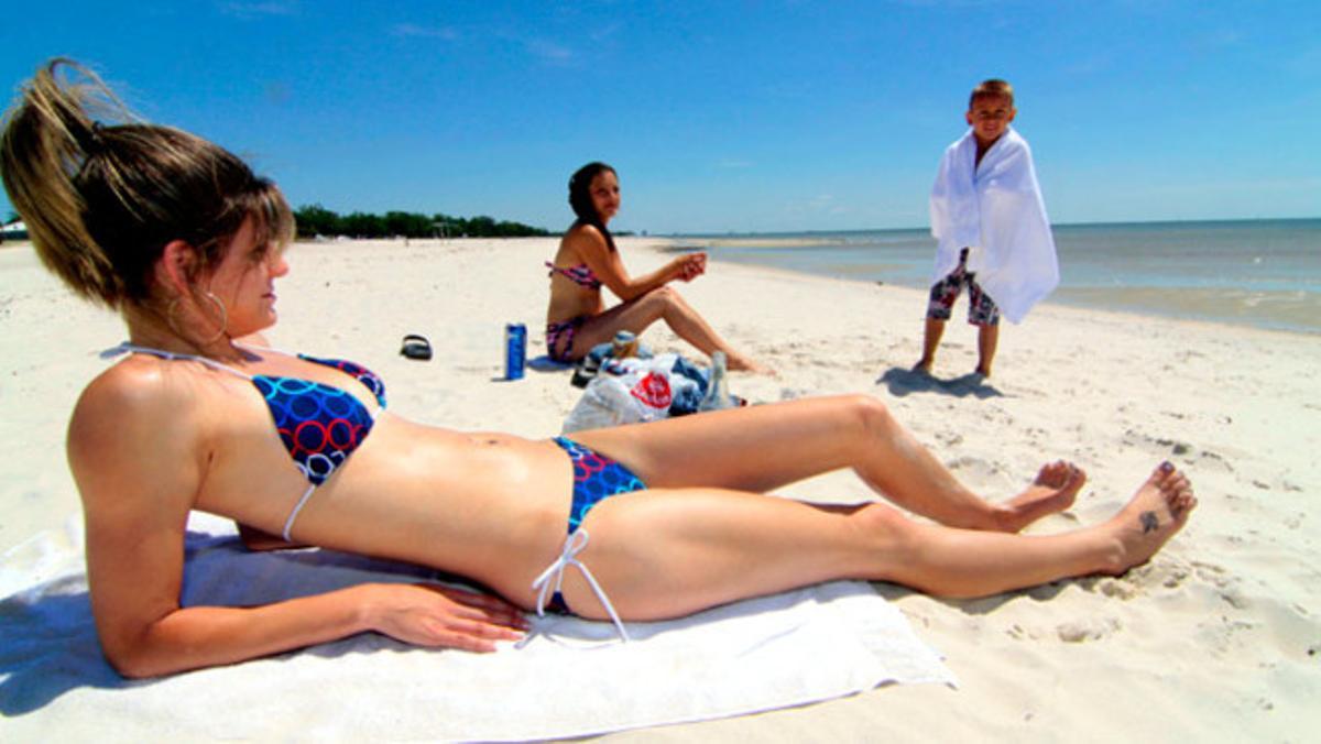 Diversos banyistes descansen en una de les platges del golf del Mississipi amenaçades per l’arribada de la marea negra de petroli.