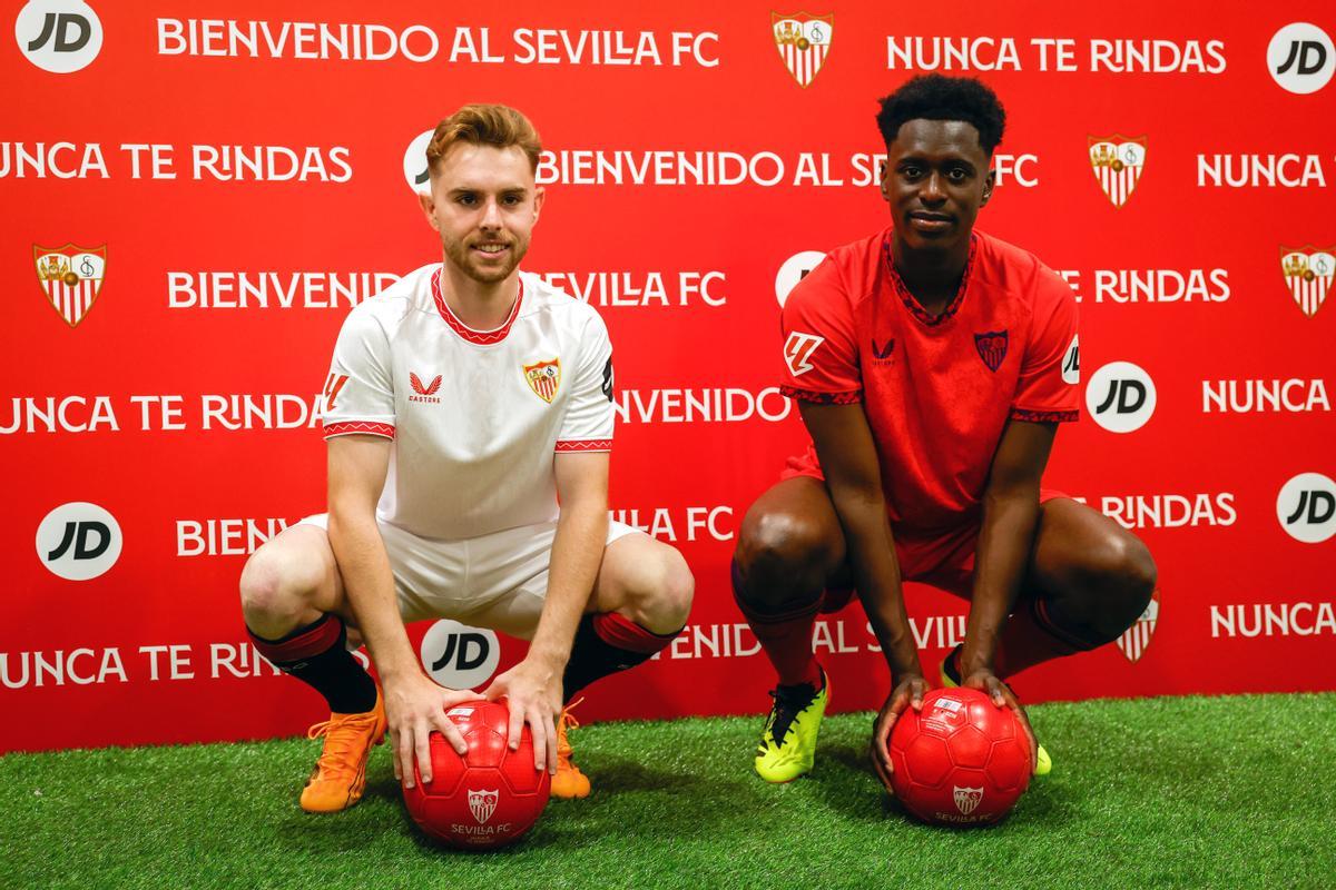 GRAFAND2556. SEVILLA, 15/07/2024.- Los futbolistas Gerard Fernández 'Peque' (i) y Sambi Lokonga (d), vestidos con las equipaciones del club sevillista durante su presentación este lunes en el Estadio Sánchez Pizjuan como nuevos jugadores del Sevilla FC. EFE/ Julio Muñoz