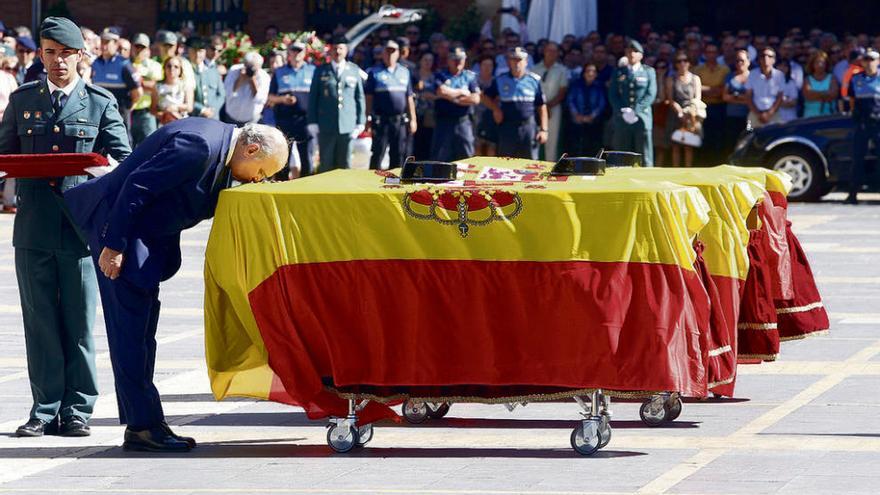 El ministro del Interior, Jorge Fernández, besa la bandera que cubre uno de los féretros.