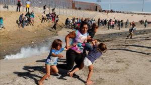Migrantes huyen de los gases lacrimógenos en el muro entre EEEUU y México, en Tijiuana