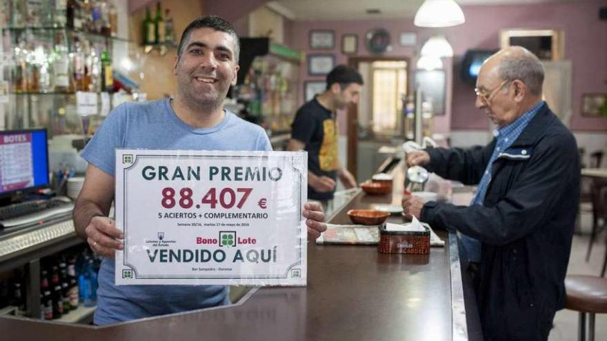 Uno de los hijos del propietario del bar San Pedro muestra el cartel del boleto ganador. // Brais Lorenzo