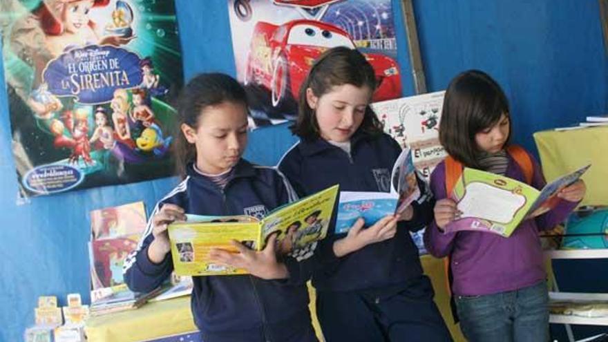 Tres niñas disfrutan de los libros de uno de los puestos .