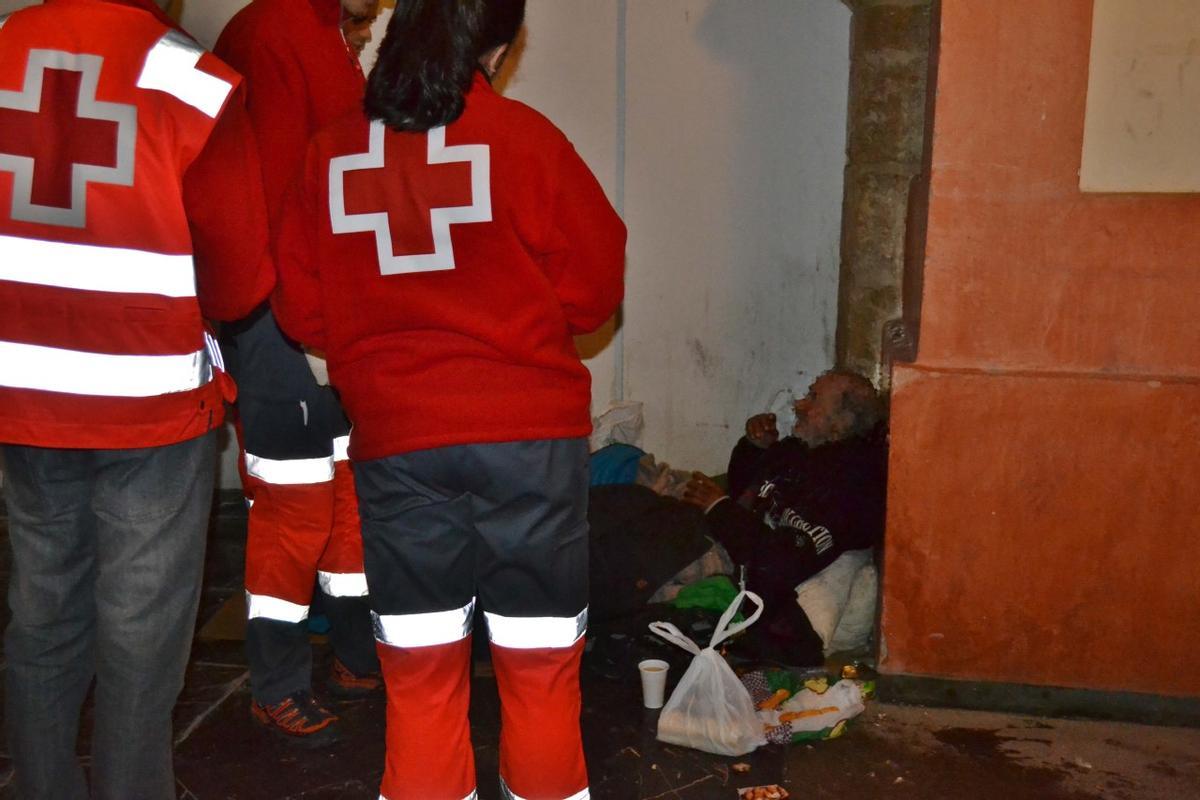 Miembros de Cruz Roja asisten a un hombre que vive en la calle en Cartagena.