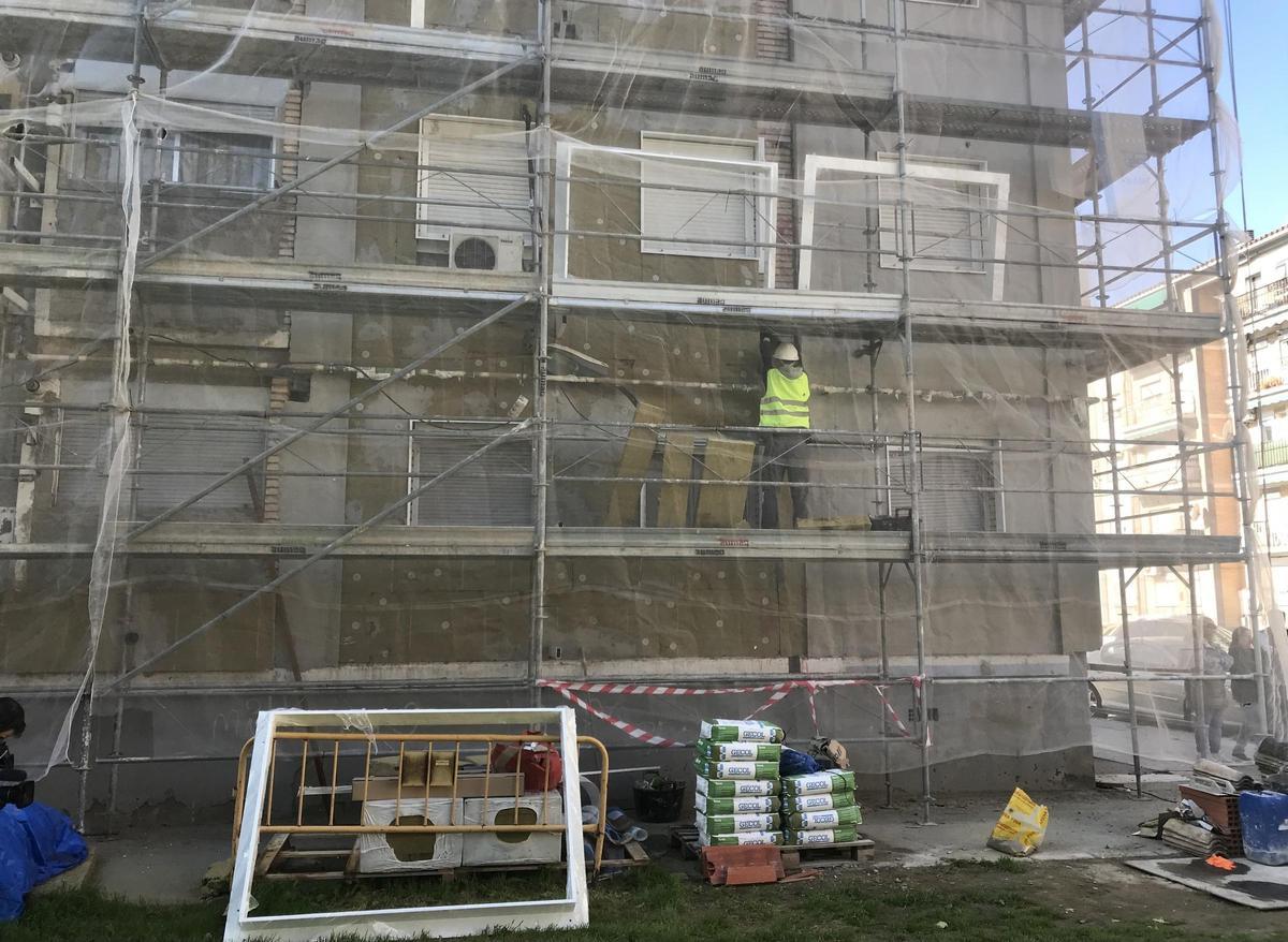 Operarios trabajan subidos a un andamio en un bloque de viviendas