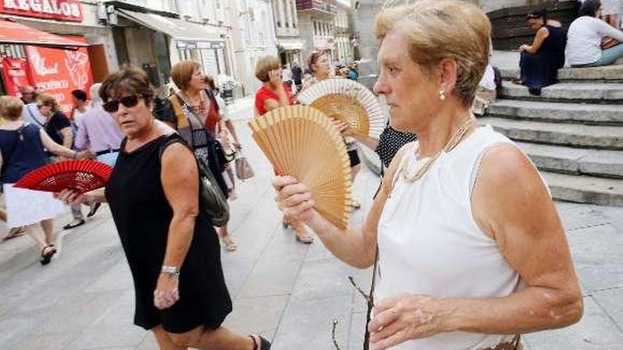 Varias mujeres, el domingo, con abanicos para paliar el calor.