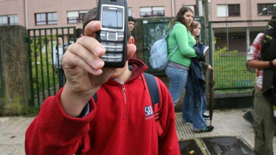 Un alumno con su móvil, a la salida del colegio, en Redondela. // Grobas