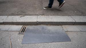 Una alfombrilla cubre una tapa de alcantarilla para evitar el mal olor en la Rambla del Poblenou, en Barcelona.