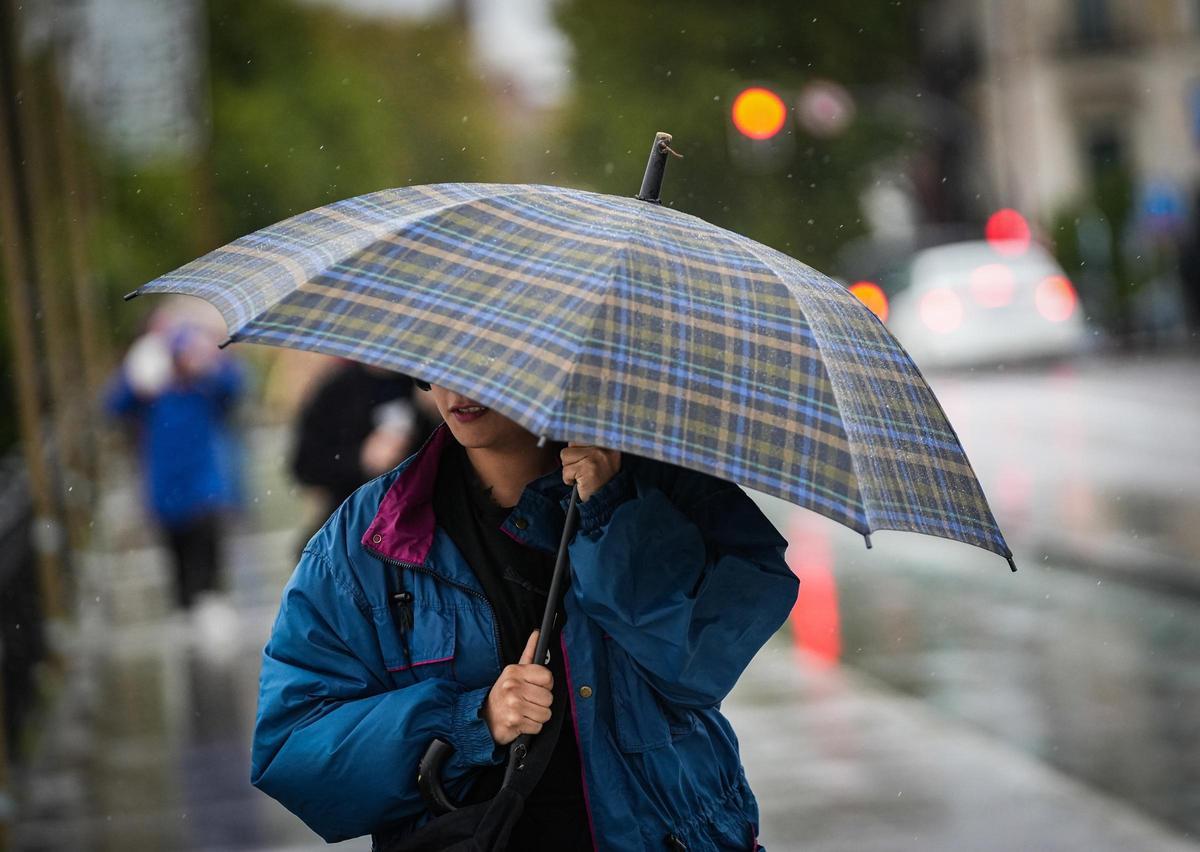 Imagen de archivo de joven protegiéndose de la lluvia y el viento.
