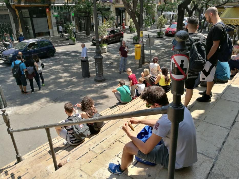 Turistas y usuarios sentados en la escalera del Mercat