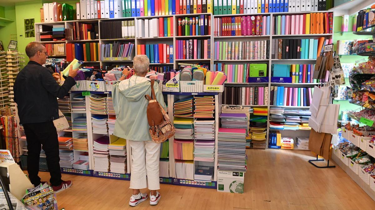 Dos personas en el interior de una librería ante numeroso material escolar
