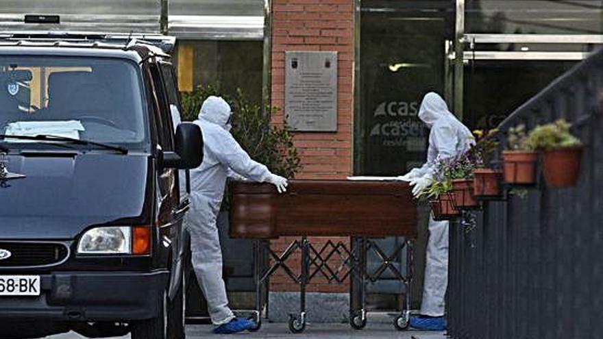 Trabajadores de una funeraria sacan a uno de los fallecidos en la residencia Caser.