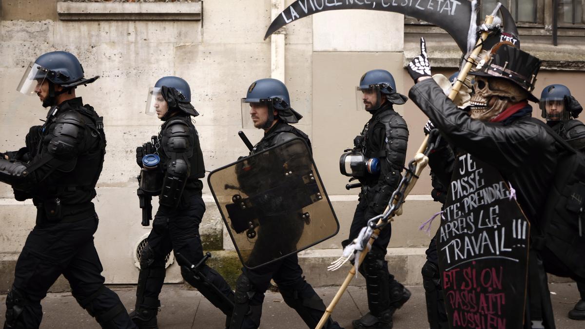 En primer pla, un manifestant contrari a la reforma de Macron, i al darrere, agents de policia