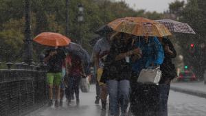 Archivo - Varias personas caminan bajo sus paraguas el día en que han puesto en aviso amarillo a la Comunidad de Andalucía por tormentas y lluvias. Imagen de archivo.
