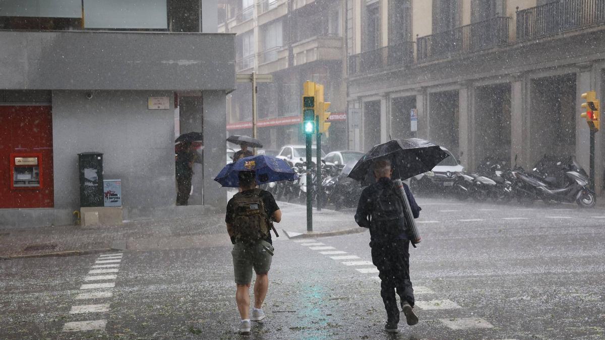 Un hombre utilizando una sombrilla para protegerse de la lluvia en Girona.