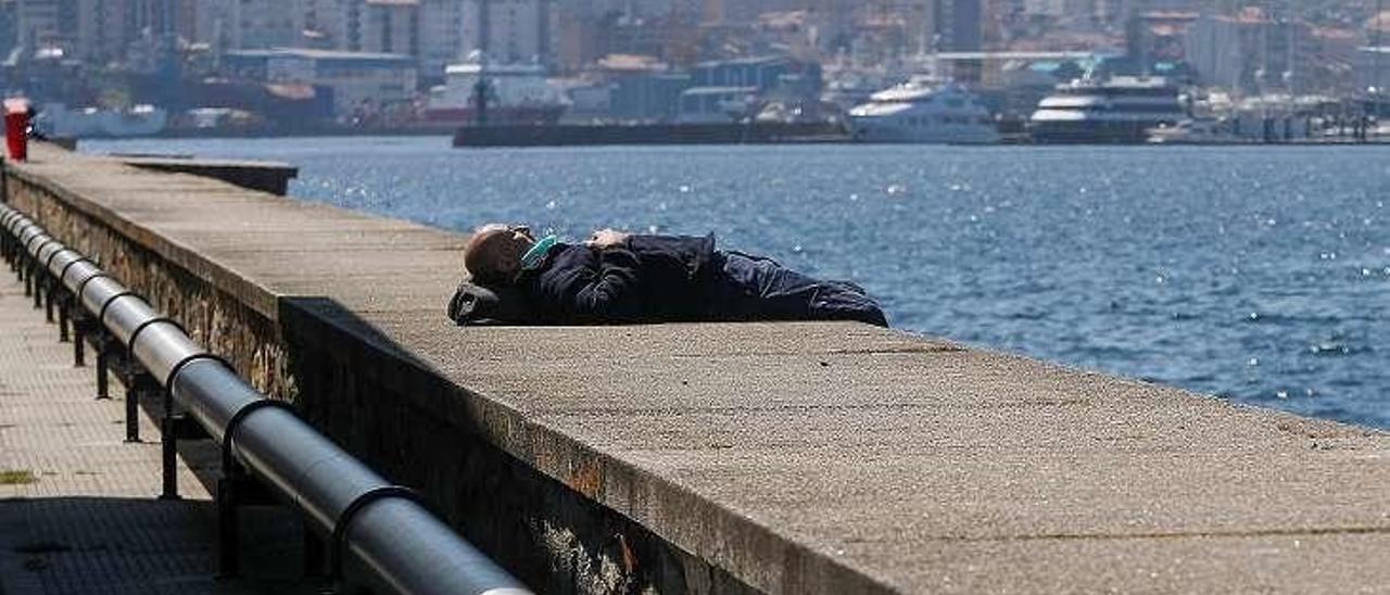 Un hombre, ayer, tomando el sol en el entorno del puerto. // R. Grobas