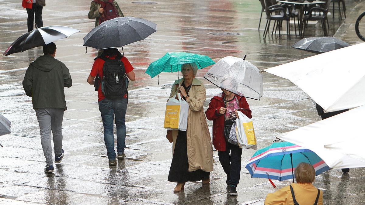 Gente pasea bajo la lluvia ayer en Ourense