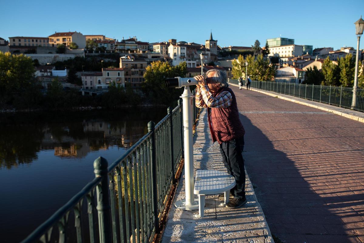 Un ciudadano mira por los prismáticos del Puente de Piedra
