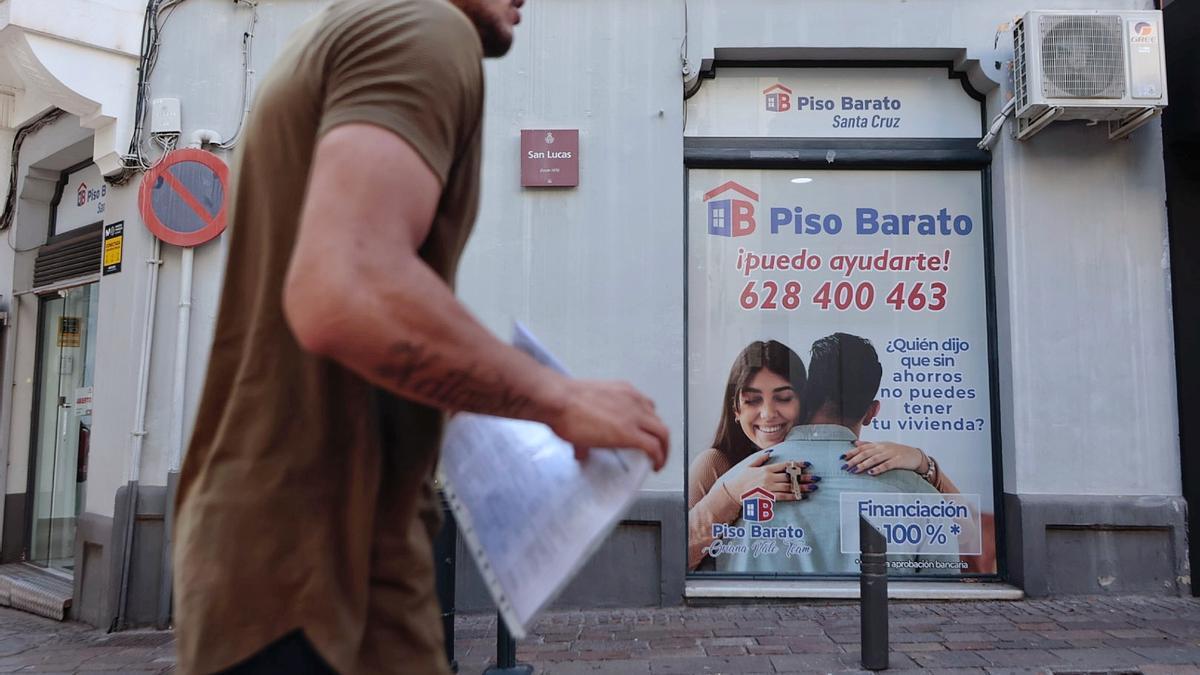 Un hombre pasa frente a un gran cartel de una firma inmobiliaria en Santa Cruz de Tenerife.