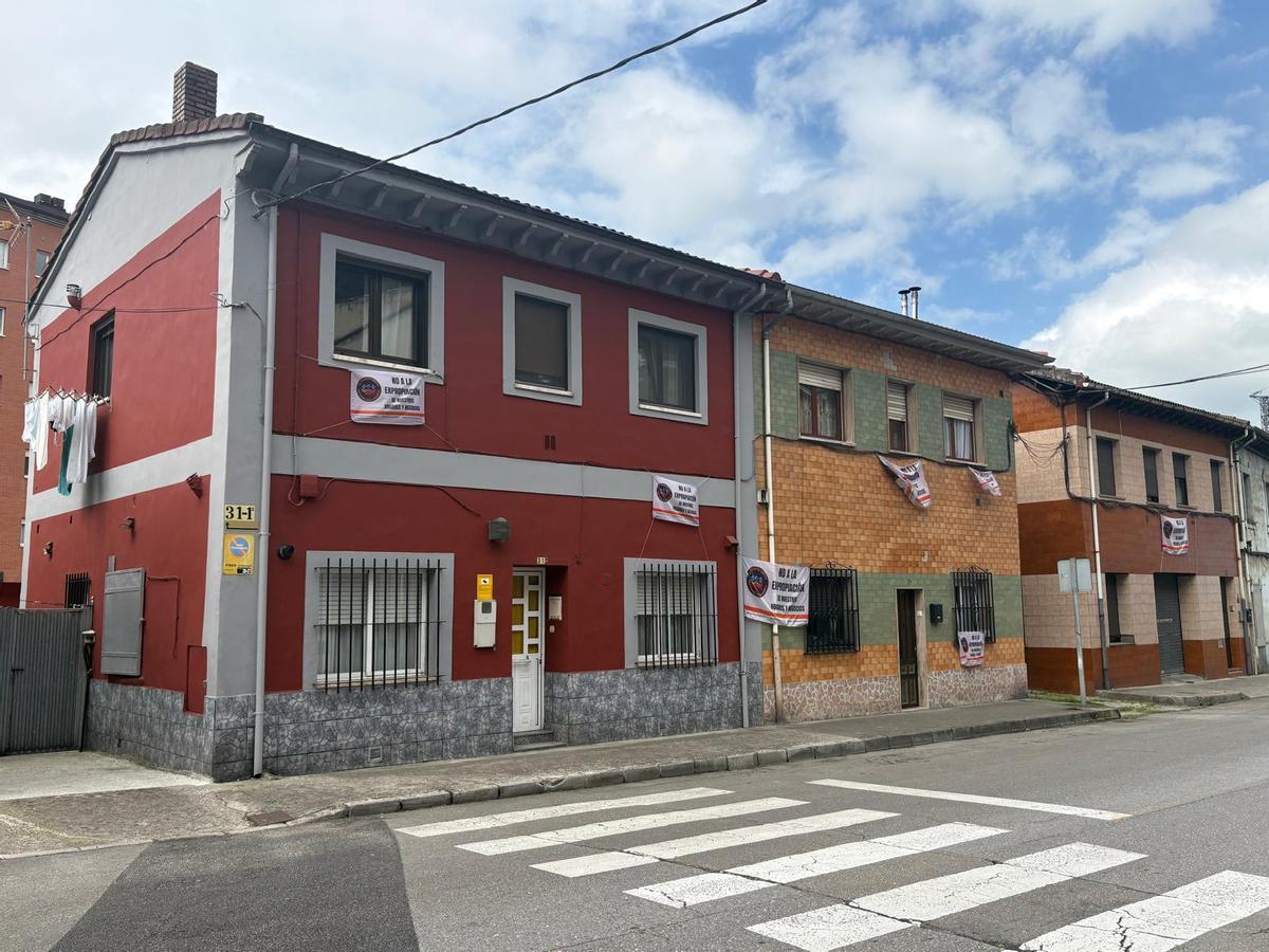 Viviendas de la calle José Álvarez Valdés, en el barrio de El Puente, en Langreo, con pancartas contra las expropiaciones
