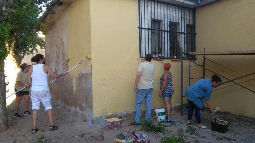 Artistas y colaboradores de TAU pintan la base del mural que crearán en la Escuela de Música.